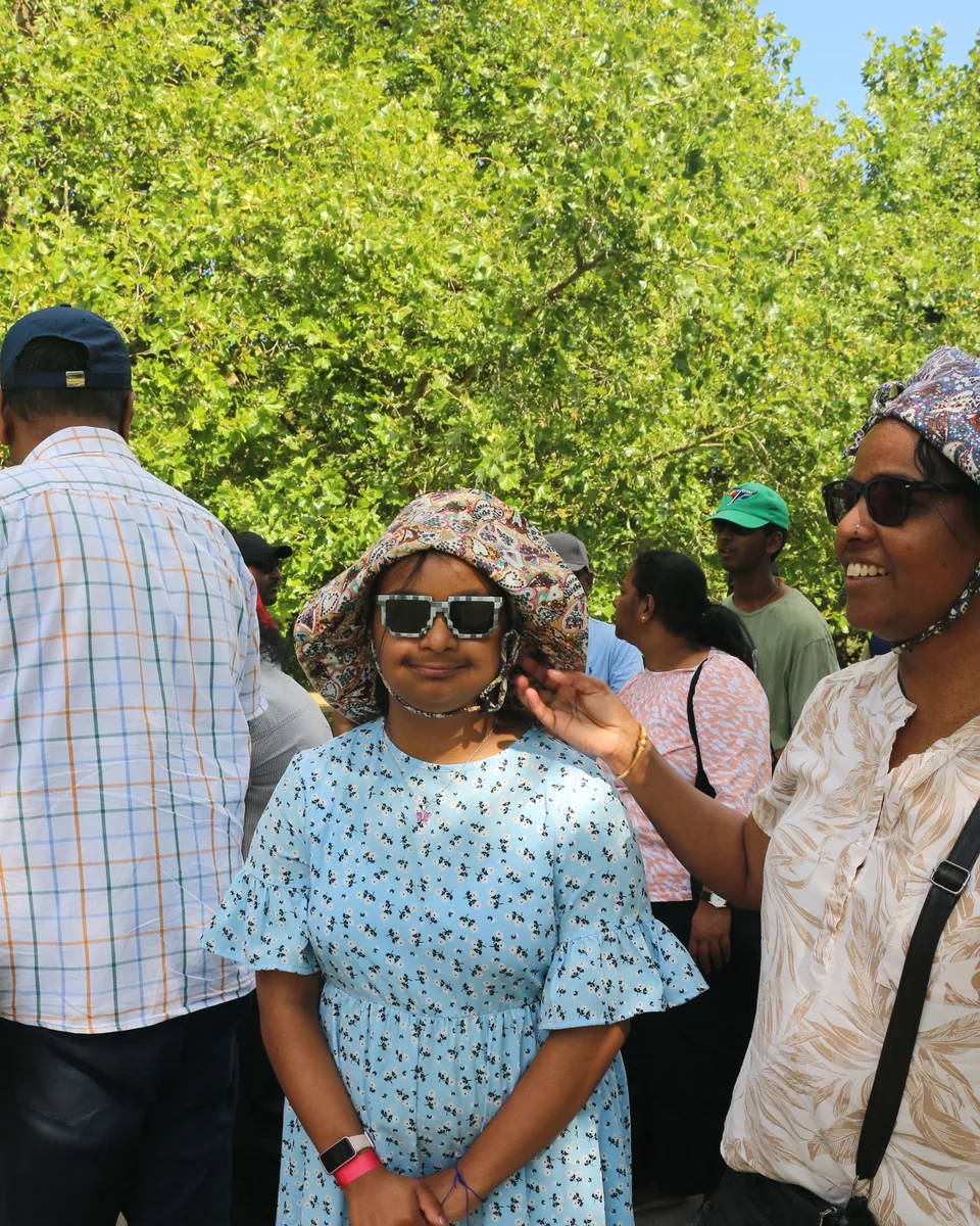 A young woman in a sun hat smiling with her family at the TSC charity walk.